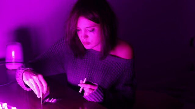 addicted woman in a den in a neon light sweater snorts drugs from the table. drug addiction