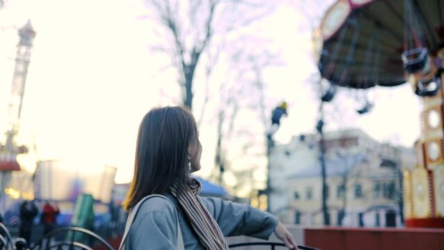 beautiful woman in an amusement park walks and smiles. Loneliness of a young woman.