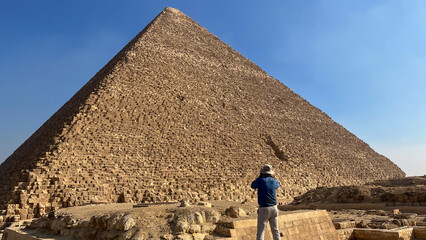 Tourist with a hat photographing a pyramid in Egypt