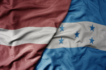 big waving national colorful flag of honduras and national flag of latvia.