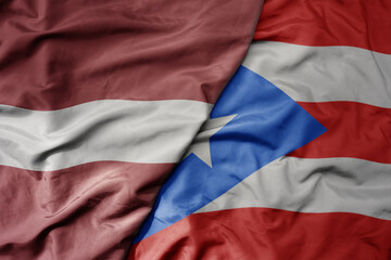 big waving national colorful flag of puerto rico and national flag of latvia.