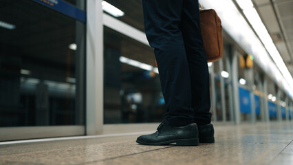 Skilled caucasian business man standing or waiting for train while holding bag. Closeup image of...