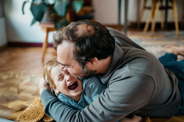 Fototapeta premium Candid capture of a father and young daughter enjoying playful moments on the floor, embodying laughter, simple life joys, and gratitude.