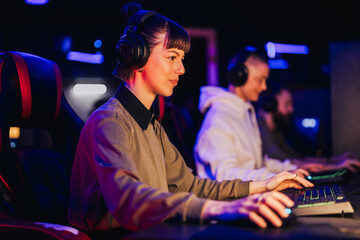 Young female gamer with headphones playing video game on a cybersport tournament