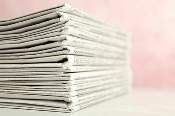 Stack of newspapers on pink background, closeup. Journalist's work