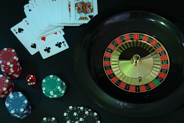 Roulette wheel, playing cards and chips on table, flat lay. Casino game
