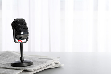 Newspapers and vintage microphone on grey table, space for text. Journalist's work