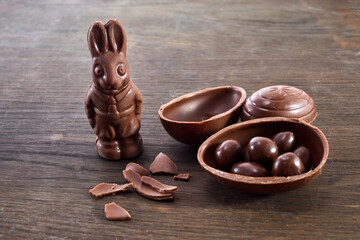 Delicious chocolate easter eggs and bunny on wooden background.