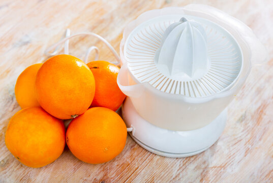 View of a citrus juicer with oranges lying next to it. High-quality image