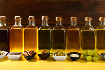 Vegetable fats. Different oils in glass bottles and ingredients on yellow table