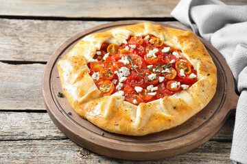 Tasty galette with tomato, thyme and cheese (Caprese galette) on wooden table, closeup. Space for text