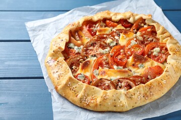 Tasty galette with tomato and cheese (Caprese galette) on blue wooden table, closeup