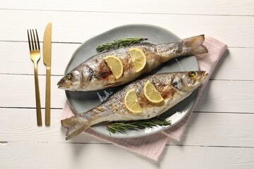 Delicious baked fish served on white wooden table, top view