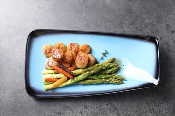 Delicious fried scallops with asparagus and vegetables on grey table, top view
