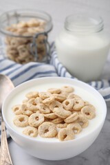 Breakfast cereal. Tasty corn rings with milk in bowl on white marble table