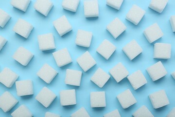 Fototapeta na wymiar White sugar cubes on light blue background, top view