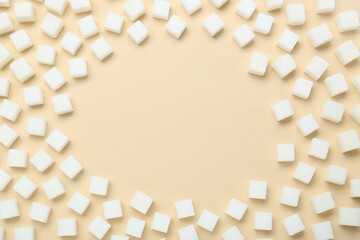 Frame made of white sugar cubes on beige background, top view. Space for text