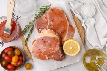 Flat lay composition with raw marinated meat, lemon and rosemary on white table