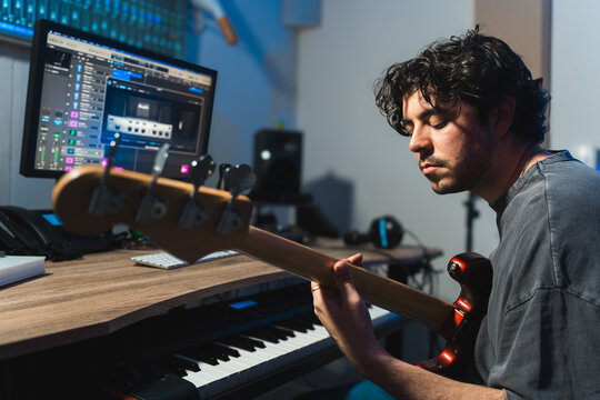 Male musician tuning bass guitar in a modern recording studio