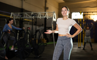 Fototapeta na wymiar Cheerful girl in sportswear standing and posing in gym