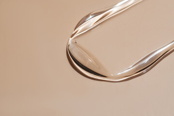 Close-up of liquid serum swatch on beige background