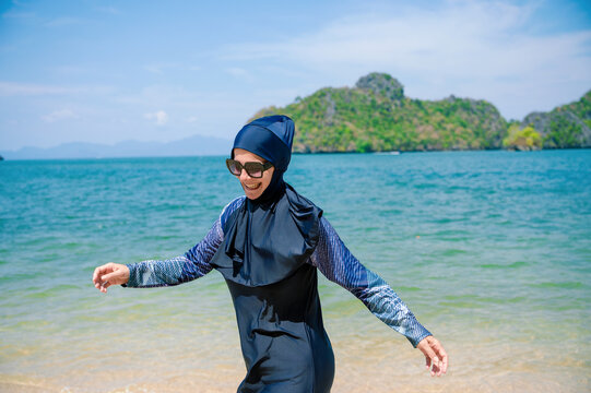 Muslim woman in beachwear enjoying seaside