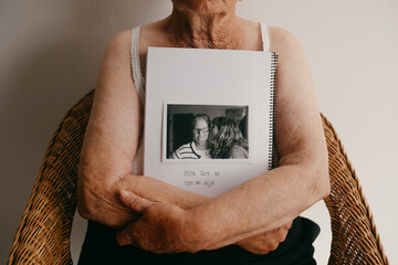 Elderly arms embracing a photo album with cherished memory