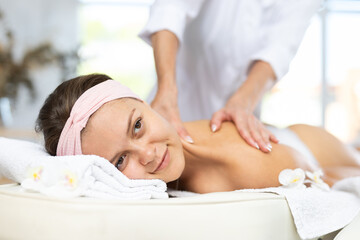 Young woman enjoying deep tissue back and shoulders massage to release muscle tension and provide...