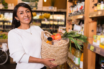 Portrait of happy woman with bag of groceries in supermarket