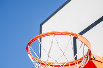 Close up of basketball hoop seen from below on blue sky background