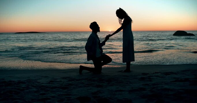 Sunset, proposal and couple at a beach with love, question or surprise romantic gesture in nature. Engagement, asking and silhouette of people at sea with support for marriage, future or commitment