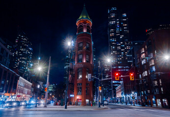 Fototapeta na wymiar Night Toronto life - historical and contemporary downtown with streets ligthts. Black and white. Historic red bricks thin building at downtown Toronto.