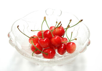Heap of Japanese cherries served in a glass bowl isolated on white background.