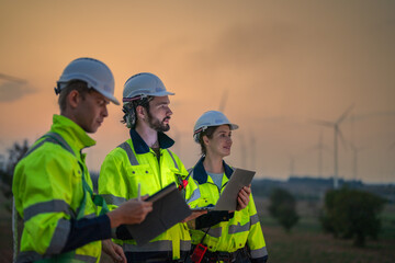 Team Engineers men and woman checking and inspecting on construction with sunset sky. people operation. Wind turbine for electrical of clean energy and environment. Industrial of sustainable.