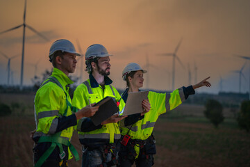 Team Engineers men and woman checking and inspecting on construction with sunset sky. people operation. Wind turbine for electrical of clean energy and environment. Industrial of sustainable.