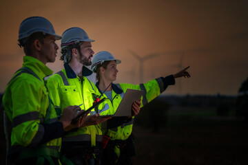 Team Engineers men and woman checking and inspecting on construction with sunset sky. people operation. Wind turbine for electrical of clean energy and environment. Industrial of sustainable.