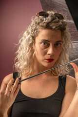 woman WITH WHITE CURLERS with an open umbrella over her head wearing a BLACK suit posing in PHOTO STUDIO