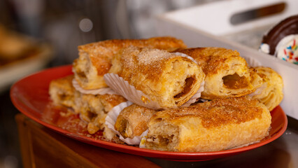 Close-up of freshly baked pastries on a red plate, showcasing their golden-brown crust and sweet filling. Perfect for food and bakery-themed projects.