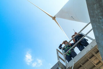 engineers working in fieldwork outdoors. Workers check and inspect construction and machine around the building project site. Wind turbines for electrical clean energy and environment sustainability.