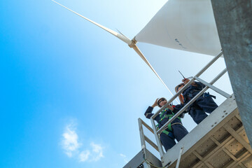engineers working in fieldwork outdoors. Workers check and inspect construction and machine around the building project site. Wind turbines for electrical clean energy and environment sustainability.