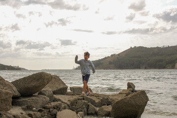 boy walking on some rocks near the sea