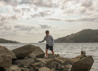 boy enjoying a walk on some rocks in a beach