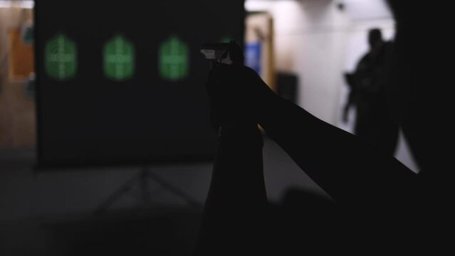 Process of shooting target at the shooting rifle range, women practicing with hand gun pistol at shooting gallery, firearms training, pointing weapon on digital screen, live fire digital targeting 