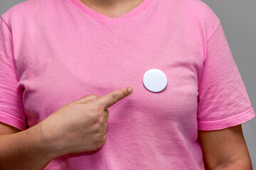 Woman in pink shirt pointing at a shiny round button. Isolated pin badge mockup