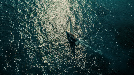Obraz premium Sparkling Solitude: The Sailboat’s Sunlit Journey