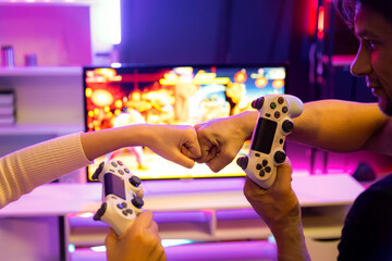 Close up of hands couple or friends joyful player video game on TV using joysticks with raising...