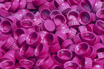 Industrial production of bottle caps made of purple high-density polyethylene. A pile of freshly cast purple HDPE plastic bottle caps. Production of beverage packaging