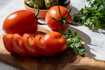 Ripe red Roma tomatoes in bowl with fresh herbs