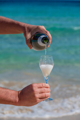 Pouring a glass of champagne on vacation, south of Fuerteventura, Canary islands, blue ocean, mountains