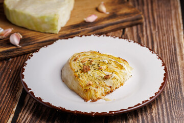 Homemade grilled cabbage steaks. Healthy vegetarian food ready to eat on a serving plate, cutlery. Wooden table background, close up